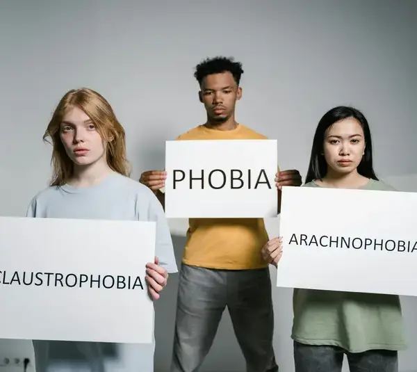 Three people hold signs with the words representing Mental and emotional health