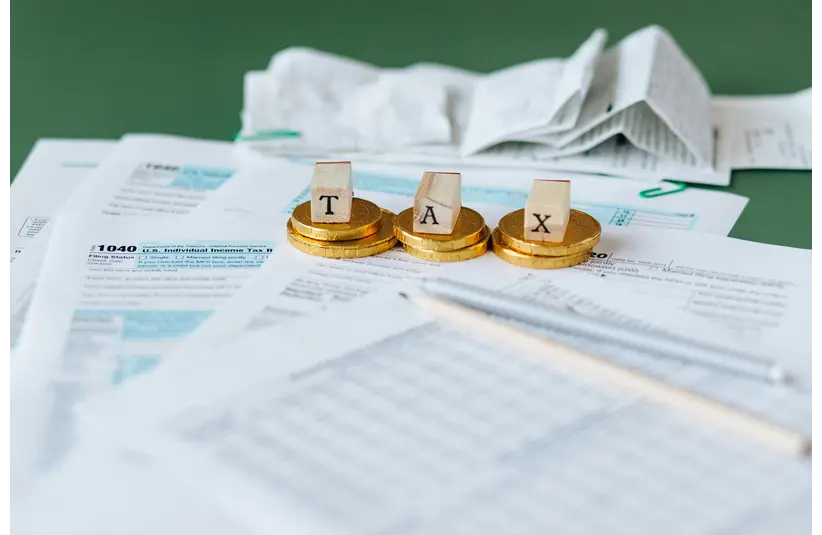 Image of TurboTax/ Tax Documents on the Table with the word "TAX" spelled out on top of the documents.