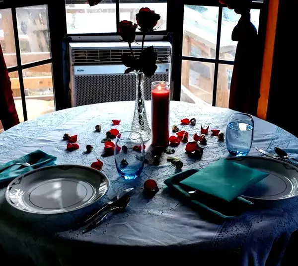 dining table set for valentines day surprise with rose petals.