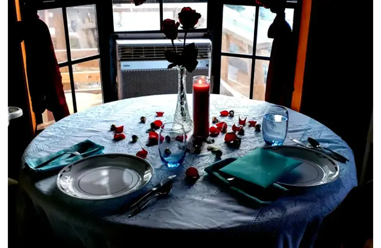 dining table set for valentines day surprise with rose petals.