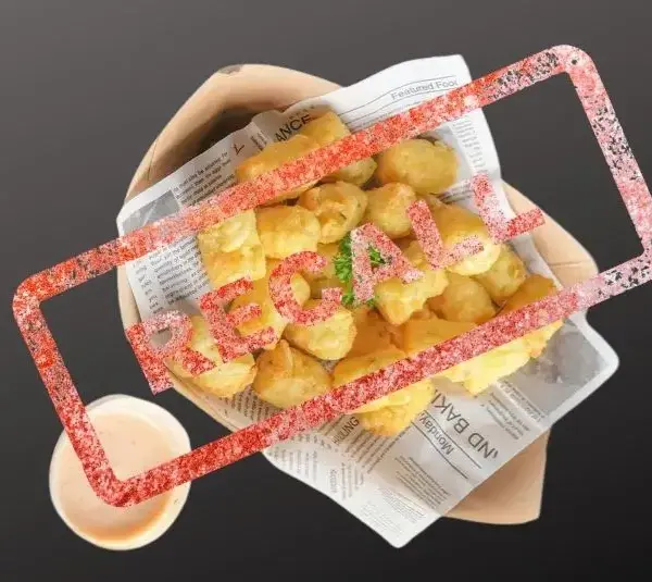 Golden tater tots on newspaper with parsley garnish, placed on a paper tray. A small cup of light brown dipping sauce is beside it with Recall stamped over it.