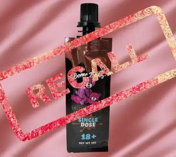 A photo features a brown pouch labeled "Boner Bears Chocolate Syrup" with a black cap and pink cartoon bear, overlaid with a red "RECALL" stamp on a pink background.