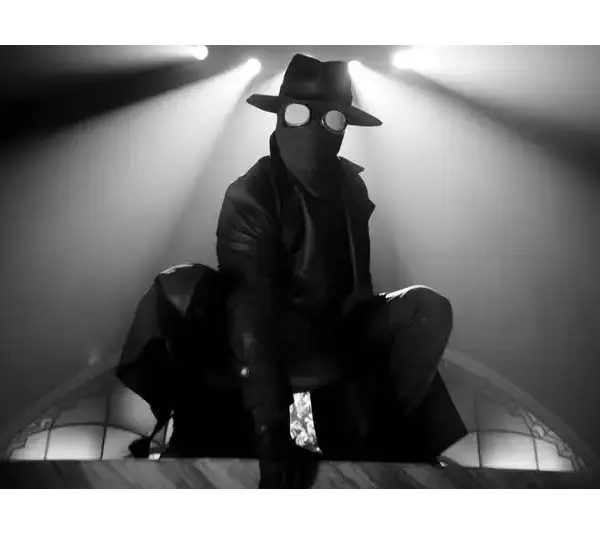 Spider-Noir crouches in dramatic black-and-white lighting. Circular glasses and a mask add intrigue; a tense, shadowy atmosphere.