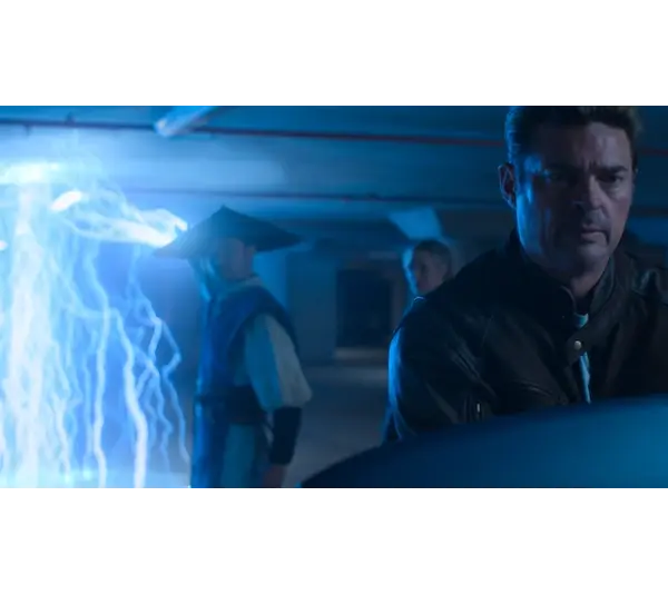 Three people, in Mortal Kombat 2, stand in a dimly lit room. Blue lightning arcs from the ceiling. The mood is tense, with focus on a man in a leather jacket in the foreground.