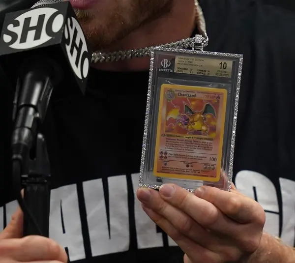 Jun 6, 2021; Miami, Florida, USA; Logan Paul holds up a Pokemon Charizard card he wears around his neck while speaking to the media after his fight against Floyd Mayweather Jr. (not pictured) at Hard Rock Stadium. Mandatory Credit: Jasen Vinlove-Imagn Images