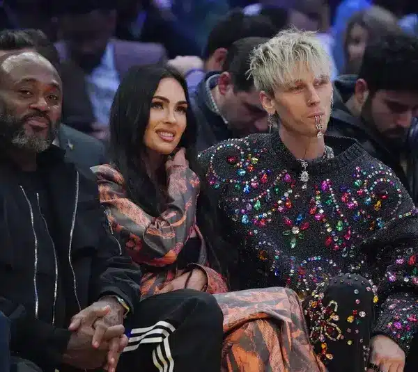 Feb 20, 2022; Cleveland, Ohio, USA; Recording artist Machine Gun Kelly (right) with wife Megan Fox (center) during the 2022 NBA All-Star Game at Rocket Mortgage FieldHouse. Fox and MGK are one of the least liked celebrity couples. Mandatory Credit: Kyle Terada-Imagn Images