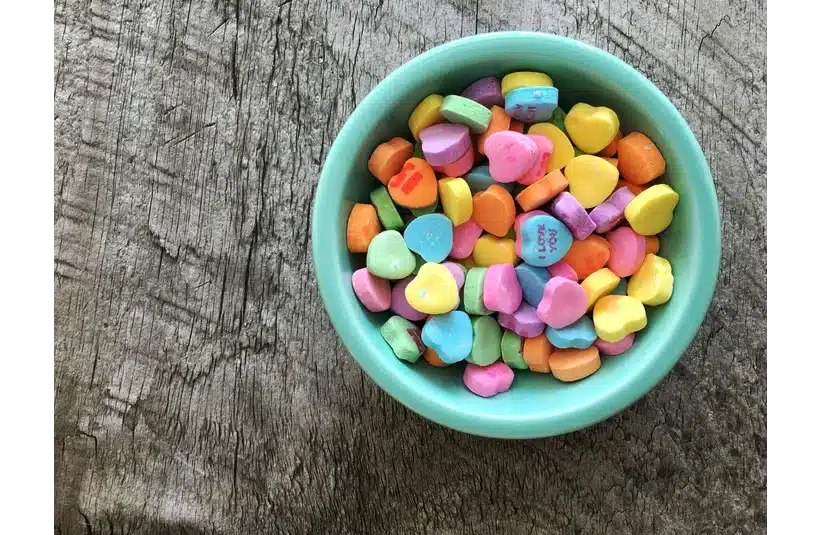 A blue bowl full of assorted colored candy hearts