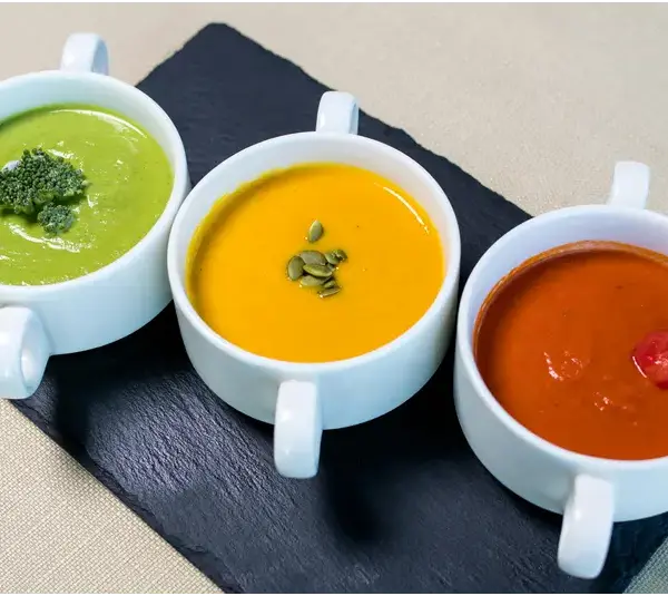 three different winter soups in white bowls