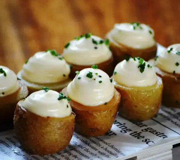 Potato appetizers with garlic mayo on a platter.