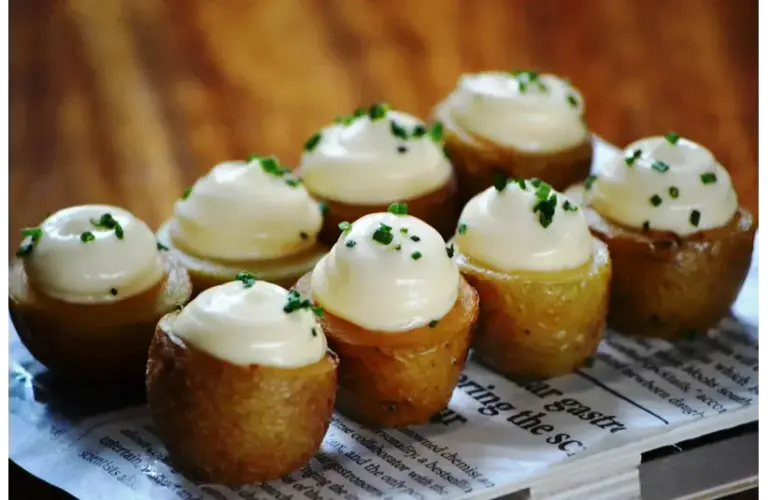 Potato appetizers with garlic mayo on a platter.