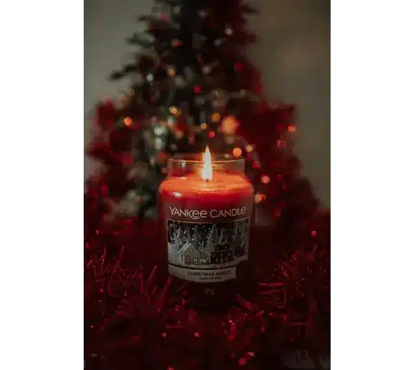 Photo of a red candle from Yankee Candle with a Christmas tree in the background