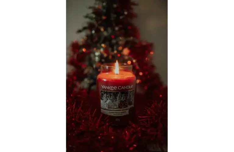 Photo of a red candle from Yankee Candle with a Christmas tree in the background