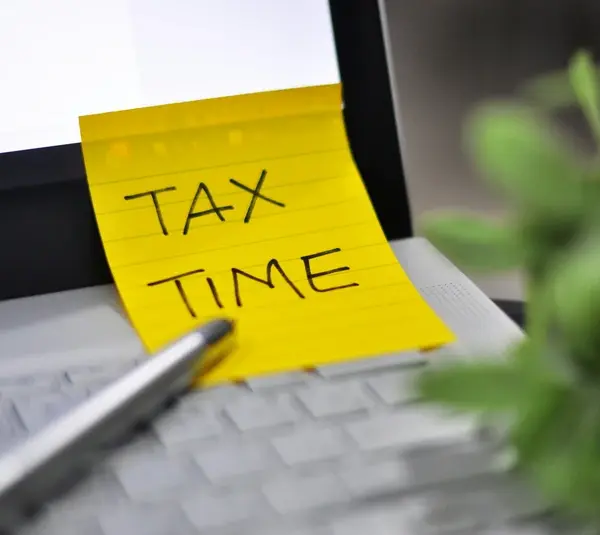 A beginner's guide to filing taxes, a computer with a sticky note that says tax time.