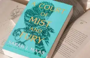 A copy of Sarah J. Maas' "A Court of Mist and Fury" lying on a pile of open books