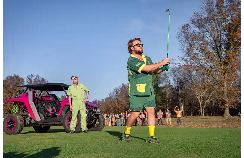 Image of a man in a green outfit playing golf on a sunny day.