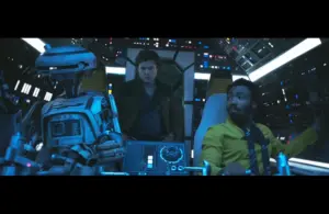 A humanoid robot with Donald Glover and Alden Ehrenreich are in a futuristic spaceship cockpit filled with glowing controls. They appear focused and determined.