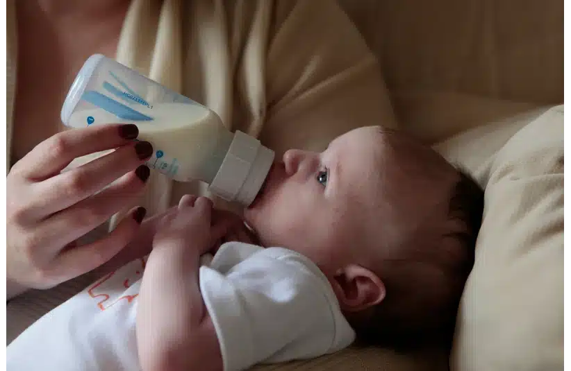 An infant being fed from a bottle, baby formula