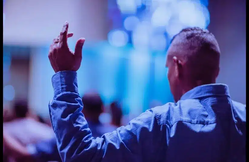 In daily devotion, a man lifts his hands in praise.