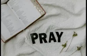 In daily devotion, a Bible is ope on white cloth background.