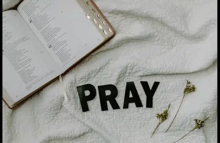 In daily devotion, a Bible is ope on white cloth background.