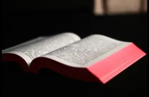 In daily devotion, an open Bible is shown on a dark background.
