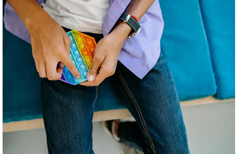 A man playing with a rainbow-colored pop-it toy.
