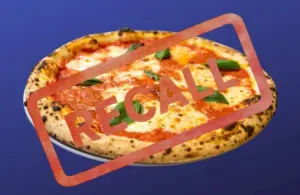 Pizza on a plate against a blue background with "RECALL" stamped in bold red letters, indicating an alert or warning about the product.