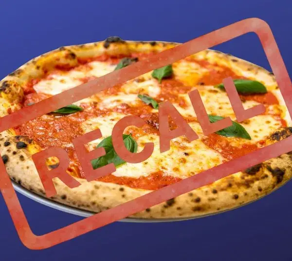 Pizza on a plate against a blue background with "RECALL" stamped in bold red letters, indicating an alert or warning about the product.