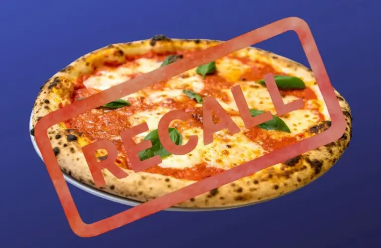 Pizza on a plate against a blue background with "RECALL" stamped in bold red letters, indicating an alert or warning about the product.