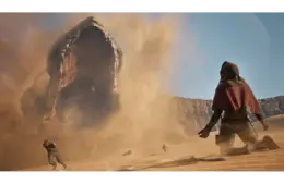 A massive sand worm emerges from the desert in Dune: Awakening, creating a dust storm. People in cloaks flee in fear under a clear blue sky, conveying urgency and danger.