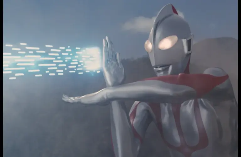 Ultraman, a silver and red robot-like figure, emits blue energy beams from its hand against a cloudy sky and mountain backdrop, conveying action and power.