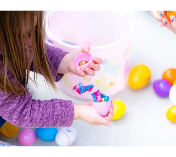 A little girl is opening her Easter eggs full of candy