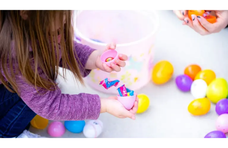 A little girl is opening her Easter eggs full of candy