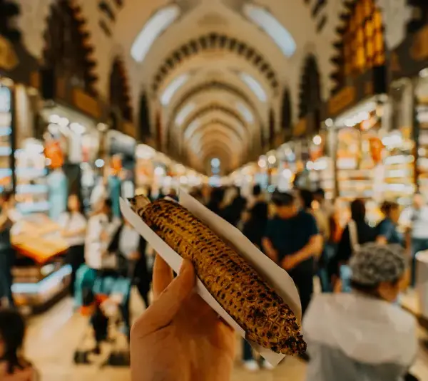 a person holding a corn while traveling and exploring destinations