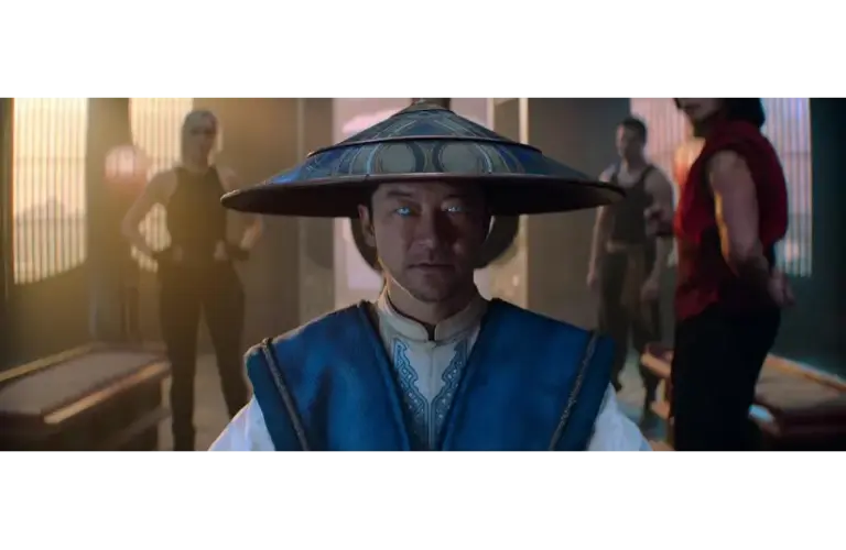Tadanobu Asano in Mortal Kombat 2 (2026), in a blue robe and wide-brimmed hat, stares intently, his eyes glowing blue. Three people stand behind him in a dimly lit room, creating a tense atmosphere.