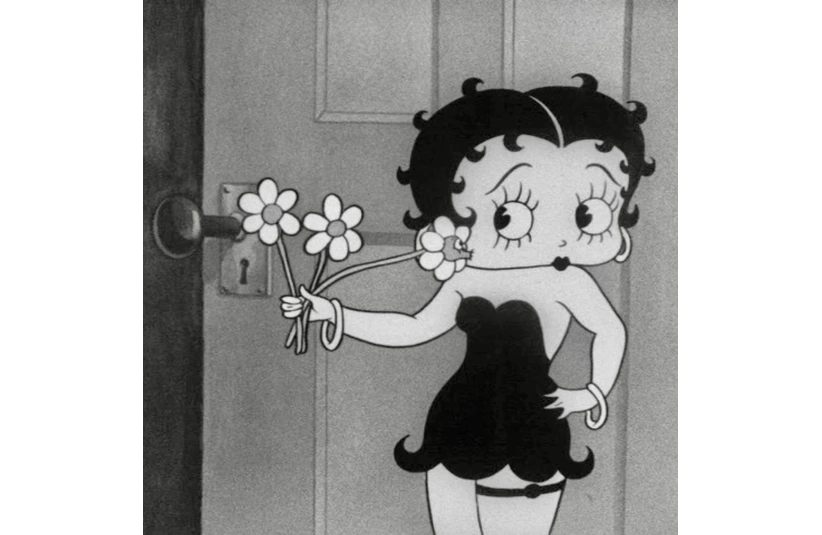 black and white shot of Bebby Boop in a black dress and holding flowers.