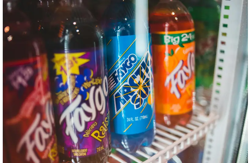 Close-up of assorted custom sodas bottled in a refrigerated grocery store display.