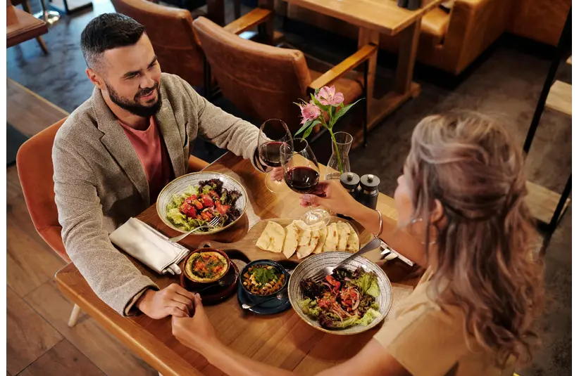Couple enjoying a romantic dinner with wine at a cozy restaurant table showing casing one of budget dates