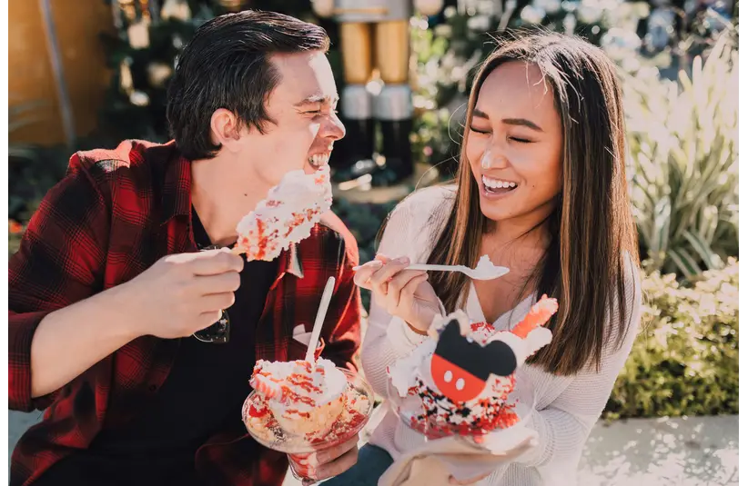 Smiling couple enjoying festive desserts outdoors during cozy dessert dates, sharing a joyful and relaxed moment together.
