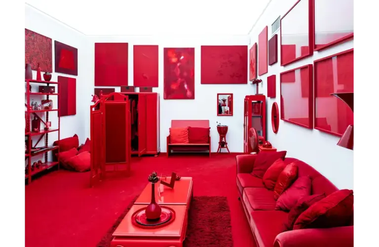 A striking, red-themed color drenched room featuring modern art pieces and furniture, creating a bold visual impact.