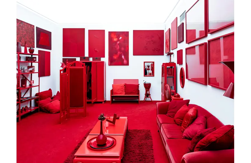 A striking, red-themed color drenched room featuring modern art pieces and furniture, creating a bold visual impact.