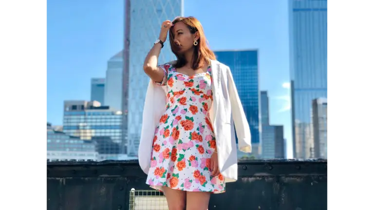 A fashionably dressed woman in a floral dress poses against a London city backdrop, highlighting the timeless appeal of floral dresses.