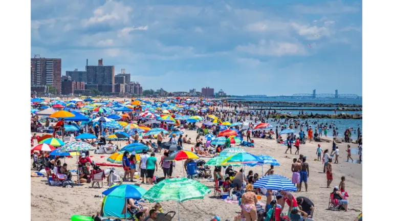 travel chaos unfolds at Coney Island as a vibrant summer scene shows beachgoers, umbrellas, and the shoreline packed with energy. August, Summer, holidays