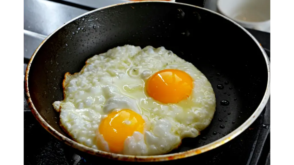 Two eggs sizzling in a frying pan with hot honey caramelizing around the edges, creating sweet‑and‑spicy honey eggs.