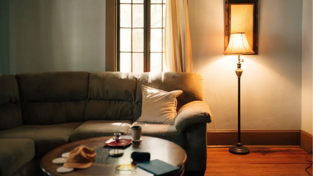 A warm, inviting living room interior featuring a sofa, coffee table, and floor lamp giving a peaceful home vibe