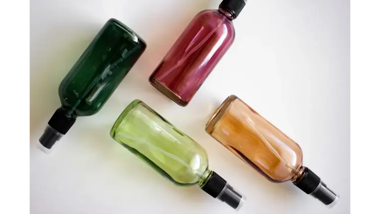Four colorful spray bottles arranged on a white surface, perfect for showcasing DIY room sprays and fresh, cozy home fragrance ideas