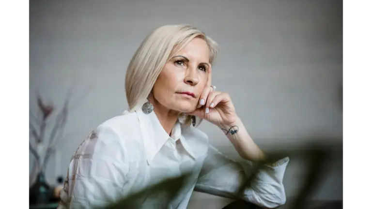 Portrait of a well-dressed senior woman embracing empowering beauty, lost in pensive thought indoors.