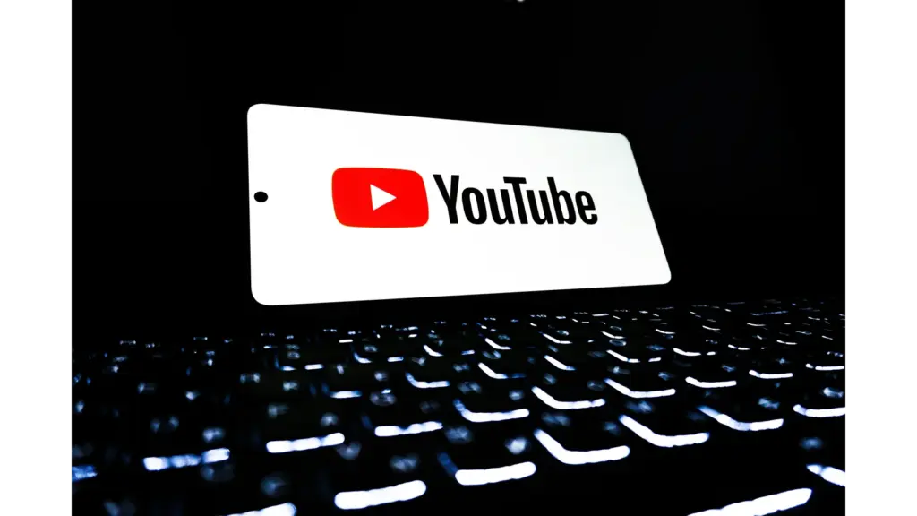 A glowing YouTube logo displayed above a dark, illuminated keyboard, symbolizing the digital world of chaos content and longform storytelling trends. YouTube Shorts