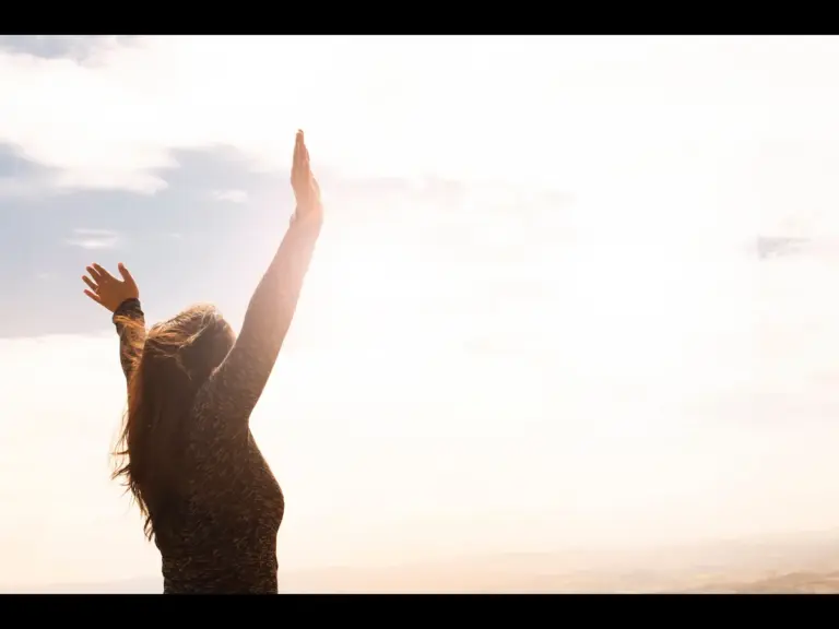 In Wednesday's daily devotional, a woman lifts her hands in surrender to God's call. 