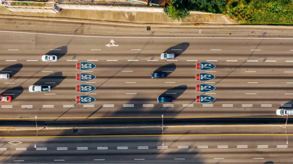 Overhead view of cars on Atlanta’s I‑85 and I‑75 highways on a sunny day, highlighting busy travel patterns influenced by changing gas prices.